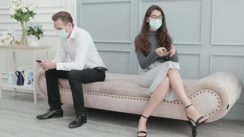 Socially Distanced Man and Woman Sitting with Phones