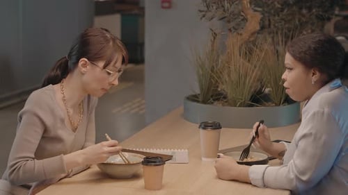 Two Female Colleagues Having Lunch Together in Cafe