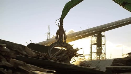A Track Material Handler is Loading Logs Onto a Conveyor at the Factory