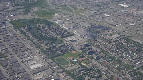 Airplane window view of city's infrastructure with residential blocks and warehouses seen