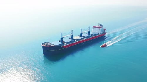 AERIAL VIEW: Flying Over Massive Ship Filled Moving in the Quiet Sea. Cargo Being Moved By Large