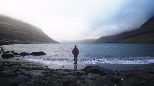Lone Figure Standing on a Rocky Beach