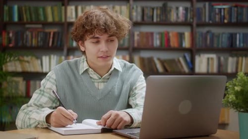 Student Studying with Laptop and Notebook in Library
