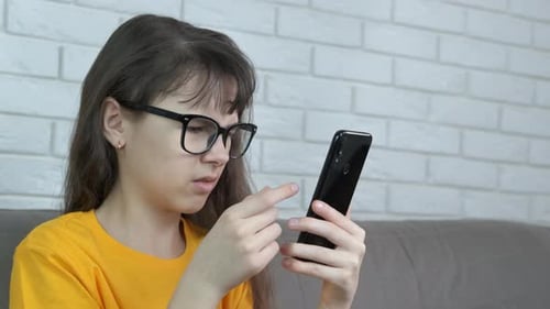 Teenage Girl Using Smartphone Sitting on Sofa