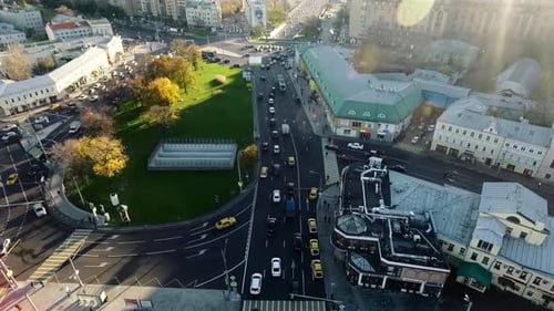 An aerial view of a small traffic roundabout in the middle of sunny urbanscape