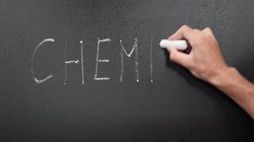Teacher writes word Chemist on school blackboard