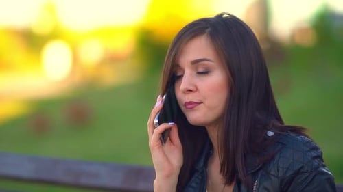 Girl in the Park, Talking on the Phone. Puts Down the Phone, Begins To Eat a Bun