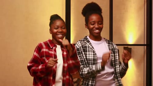 Two Happy Sisters Dancing in Living Room at Evening