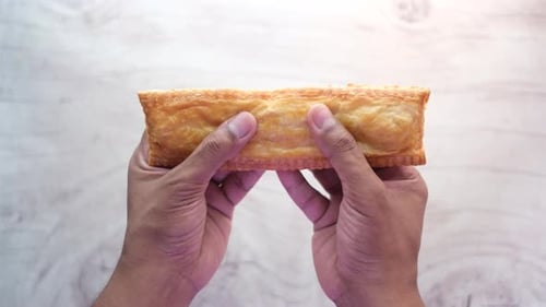 Hands Dividing Golden Brown Puff Pastry