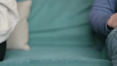Close Up of Man Holding Hands of Woman While Sitting on Sofa