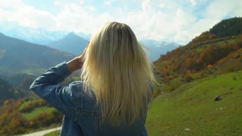 woman straightens her hair and enjoys the nature of autumn mountain landscape.