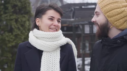 Close-up of Young Caucasian Couple Strolling Along Winter Street. Happy Man and Woman Talking