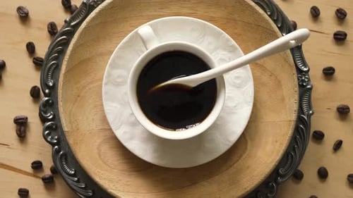 Top View of Coffee with Spoon on Decorative Plate on Wooden Table