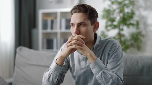 Young Guy Lost in Thoughts Sitting on Couch