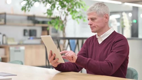 Pensive Middle Aged Man Using Tablet