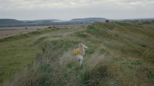 Back View of Female Child Walking Alone Among High Grass