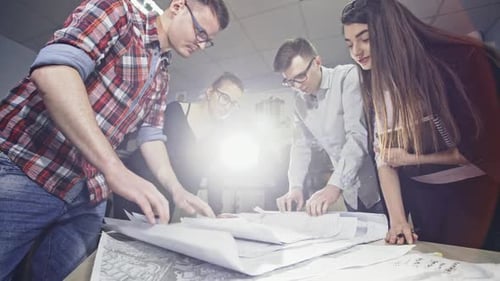 Team of Architects Studying Plans at Table