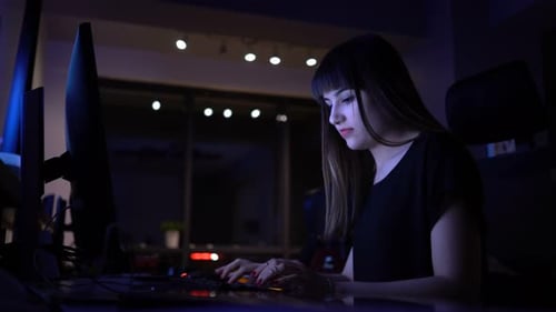 Woman Typing on Computer at Dark Workplace