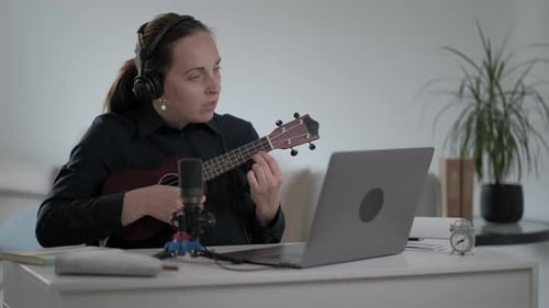 Woman Playing Ukulele at Desk at Home