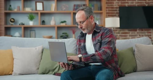 Middle Aged Man Using Laptop on Sofa
