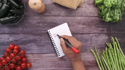 Young Man Writing Diet Pan on Notepad on Kitchen Table