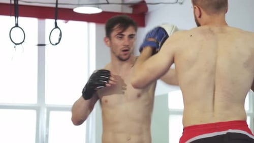 Treinamento de kickboxer atlético bonito com seu treinador na academia