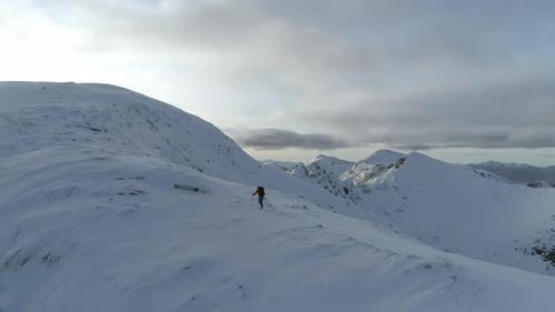 Mountain Climber Climbing Towards the Summit of a Snowy Mountain