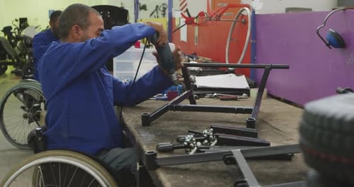 Man in Wheelchair Using Drill in Workshop