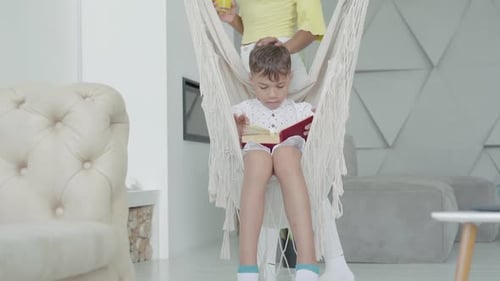 Boy Reading Book in Hammock in Living Room