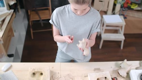 Female Artist Sculpting Plaster Figure in Home Studio
