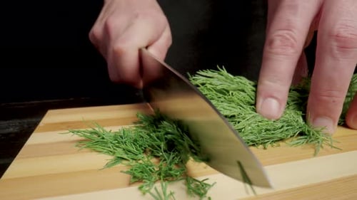 Male Hands with a Knife Cutting Green Dill Sprigs