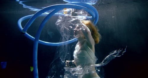Frau sinkt im Schmutzwasser des Ozeans, Müll schwebt herum