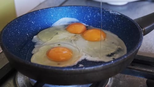 Petit déjeuner à la maison Les œufs frits sont cuits dans une poêle dans la cuisine familiale