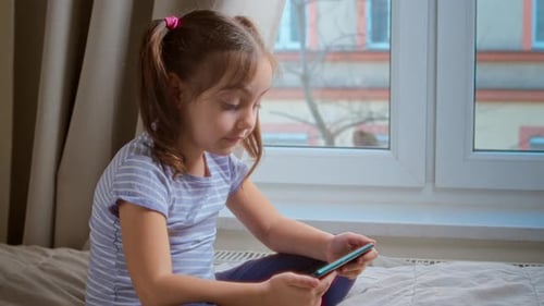 Girl Watching Phone Indoors Sitting on Bed