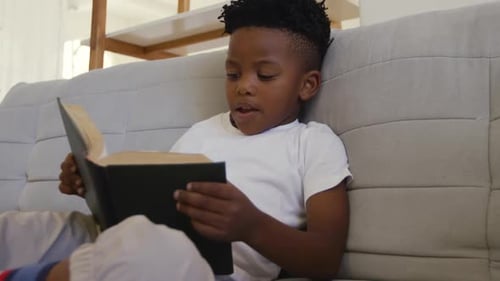 Young Child Reads a Book on a Couch