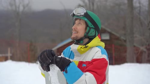 Closeup Shot of a Young Man Wearing a Helmet with a Snowboard in a Mountain Resort. Winter Holidays