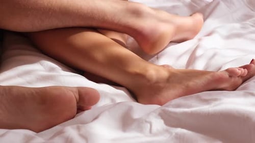 Young Couple in Bed Making Love Top View on Legs Bedding