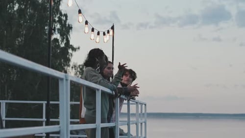 Friends Gather on Deck Overlooking Water at Sunset