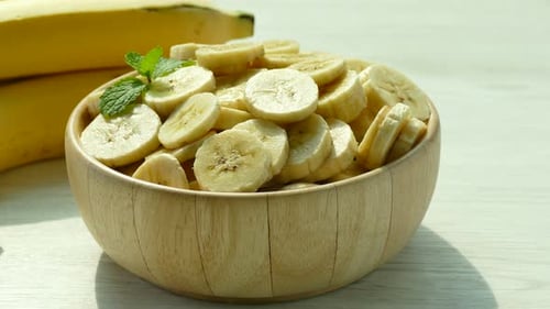 Bowl of Fresh Banana Slices and Whole Bananas