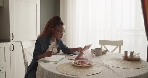 Woman Studying at Kitchen Table with Tablet