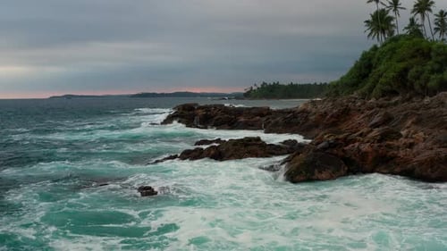 Ocean Waves Crash Against Stony Rocks During Sunset on the Island of Sri Lanka, Aerial View