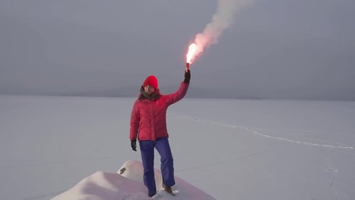 Woman Signals with a Flare in Snowy Landscape