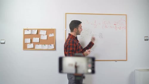 Man Explains Math Problems on Whiteboard for Video