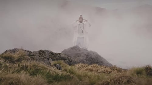 Um modelo caucasiano masculino estende os braços no ar cheio de neblina