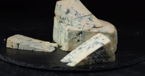 Les morceaux de fromage brie sur une planche en pierre tournent lentement