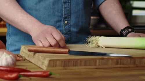 Vidéo de suivi rapprochée de poireaux jetés dans la cuisine.
