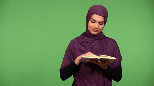 A Young Beautiful Muslim Woman Reads a Book Green Screen Background