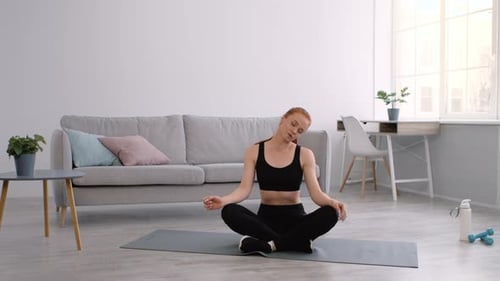 Woman Stretching Neck on Yoga Mat at Home