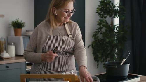 Mature Woman Peels Carrot in Kitchen