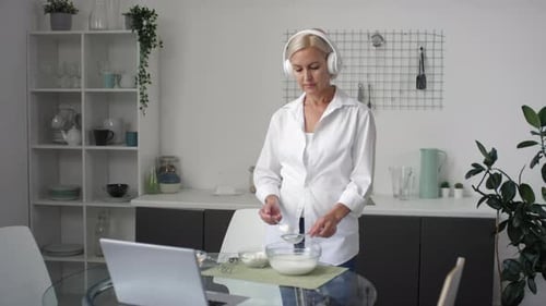 Woman Adding Ingredients to Bowl in Kitchen